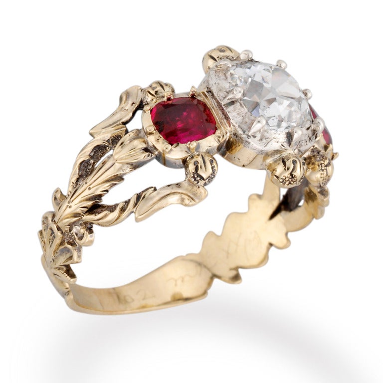 A Victorian ruby and diamond three stone ring, the cushion-cut diamond estimated to weigh 1.20 carats to the centre of two cushion-cut rubies weighing an approximate total of 0.50 carats, all cut-down set to a yellow gold fancy leaf-shaped pierced