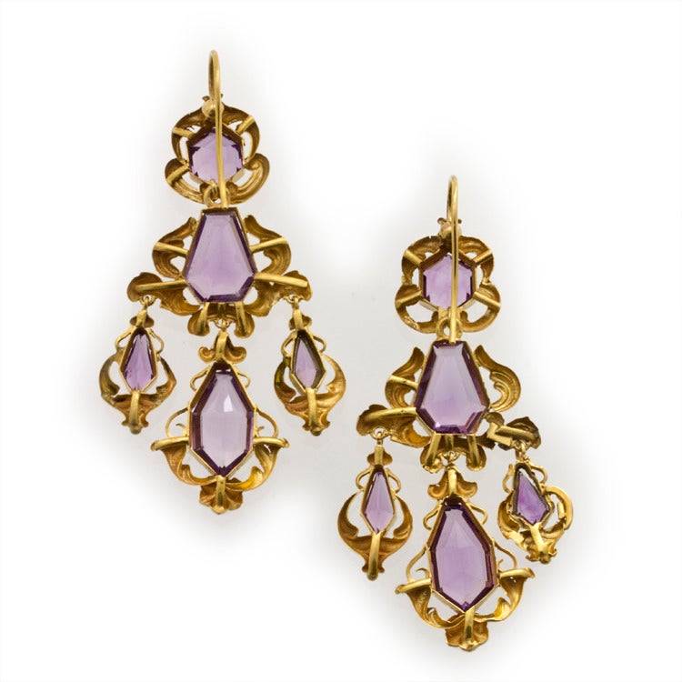 A pair of Victorian amethyst and repousse gold scroll motif earrings, each drop comprising a hexagonal-shaped faceted amethyst to the top, a kite shaped faceted amethyst to the centre with three graduated amethyst drops beneath weighing a total of