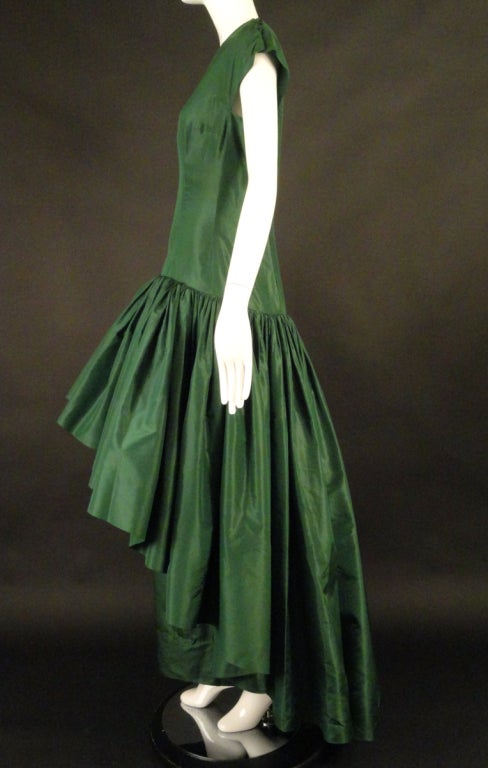 Stunning and VERY rare is this c.1970 couture evening gown in a dark forest green silk taffeta. My opinion is the gown was a special request from a 1950s model pictured here. It's the same gown only with a more modest bodice.  The gown has a scoop