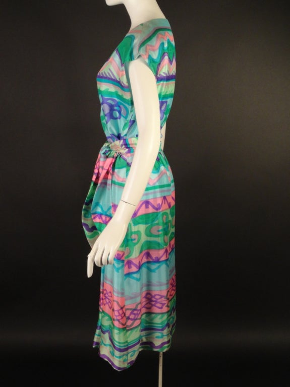 Wonderful spring and summer dress from the 1960s. The silk dress is hand painted in green, aqua, turquoise, pink, lilac and purple. The wrap dress has a plunging v-neckline and an elastic waist casing and snap and hook closures across the front. 