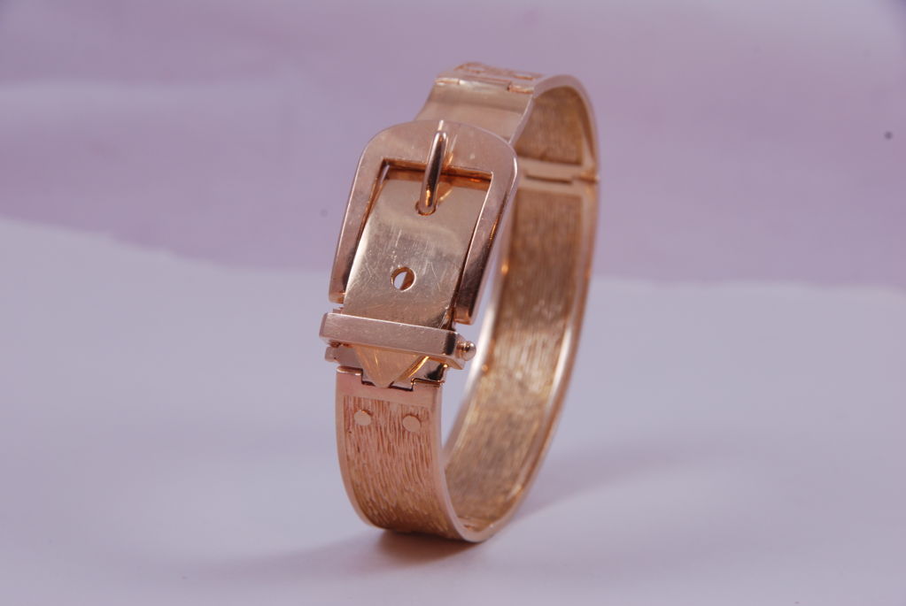 Heavy 14K yellow gold hinged buckle bracelet. Bracelet opens and buckles like a regular belt and is adjustable to three sizes. The front of the bracelet has a smooth polished finish and the sides are rear are textured with fine detailing.<br />
<br