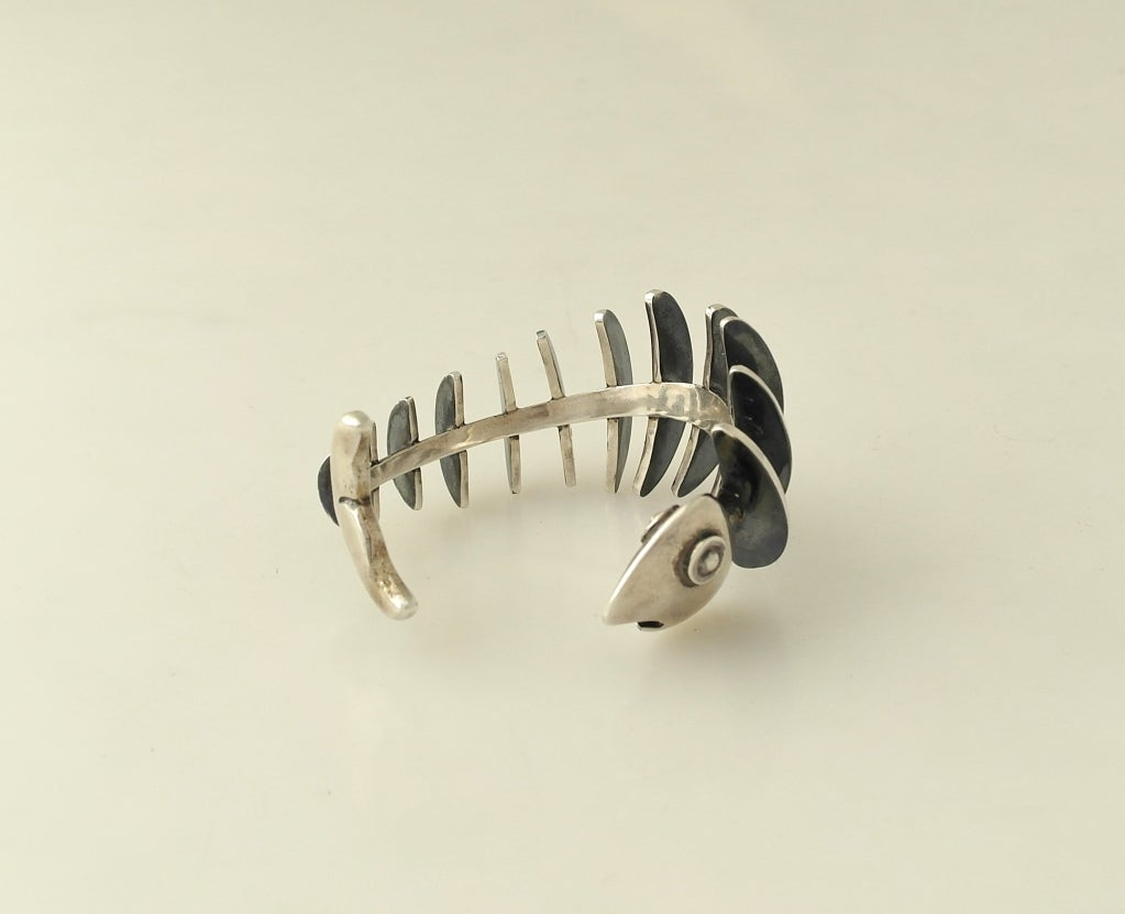 Being offered is a circa 1956 .970 silver cuff bracelet by Antonio Pineda of Taxco, Mexico, in an abstract 3-dimensional fish skeleton motif Antonio Pineda abstract cuff bracelet. 

Approx 6 1/2