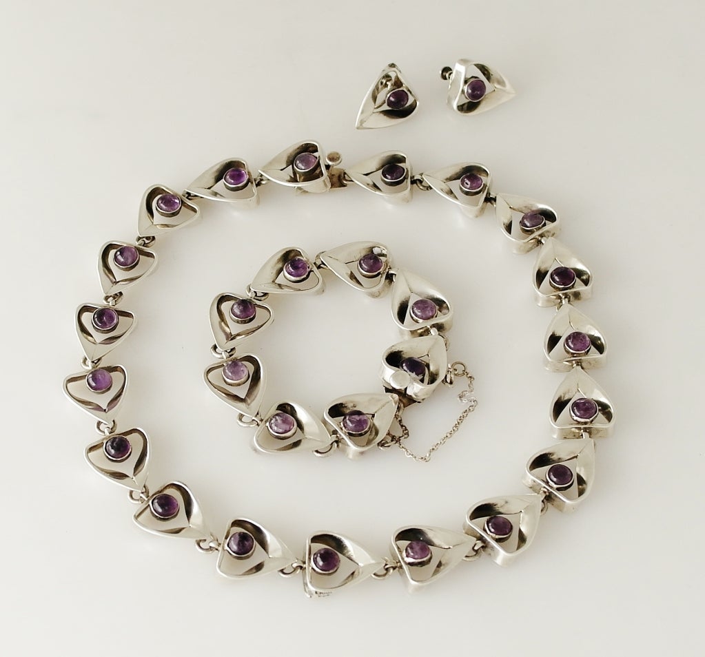 Being offered is a circa 1960 sterling silver and amethyst necklace, earrings & bracelet set by celebrated designer Emma Melendez of Taxco, Mexico, each cabochon amethyst presented in a heart shaped dimensional setting.  Necklace 18 inches long;