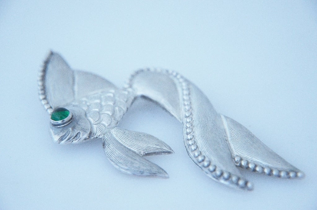 Being offered is a large circa 1965 sterling silver brooch by Los Castillo, of Taxco, Mexico, featuring a fish with an oversized long tail, the body engraved to create scales, with green glass eye.
Measures 3 3/4 inches by 2  inches.  Marked.  In