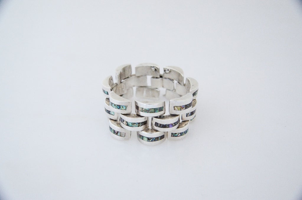 Being offered is a circa 1990 sterling silver and abalone bracelet by Gerardo Lopez of Taxco, Mexico, in a chunky moderne motif, each link featuring a strip of abalone.  Measures  8