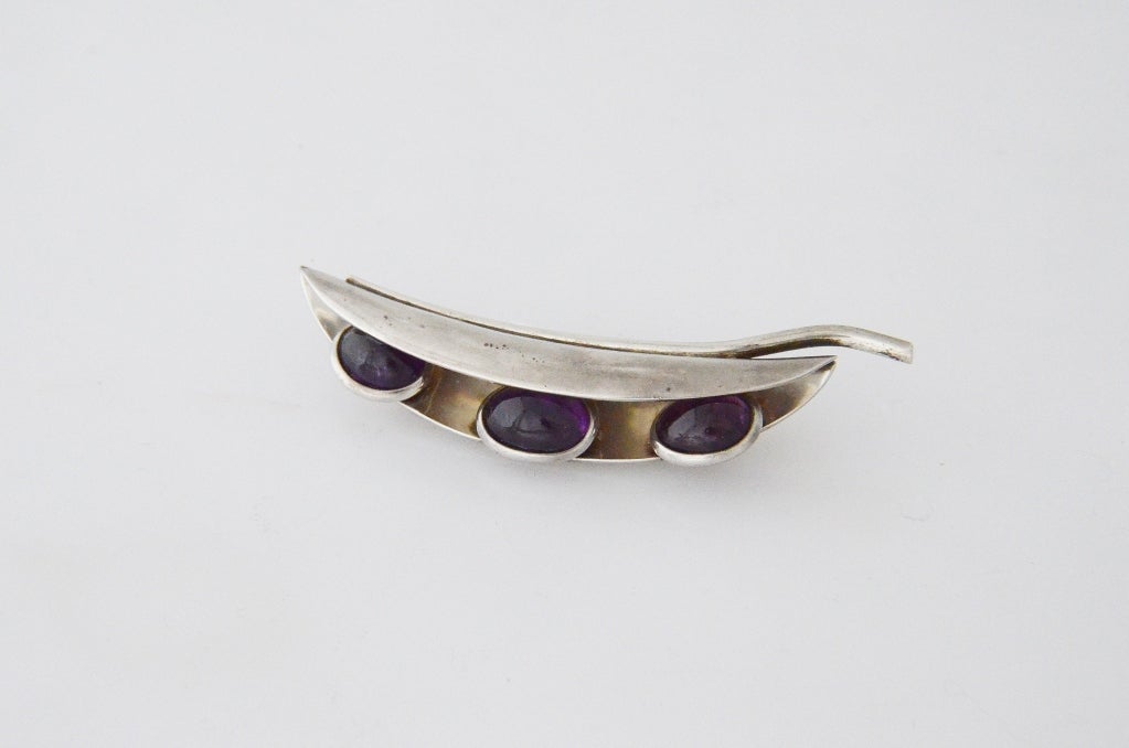Being offered is a circa 1965 sterling silver brooch  by Antonio Pineda, of Taxco, Mexico, in a 'pea pod' motif but instead of peas in the pod there are three (3) cabochon amethysts.     Dimensions 3 1/2 inches long by 3/4 inches.  Marked as