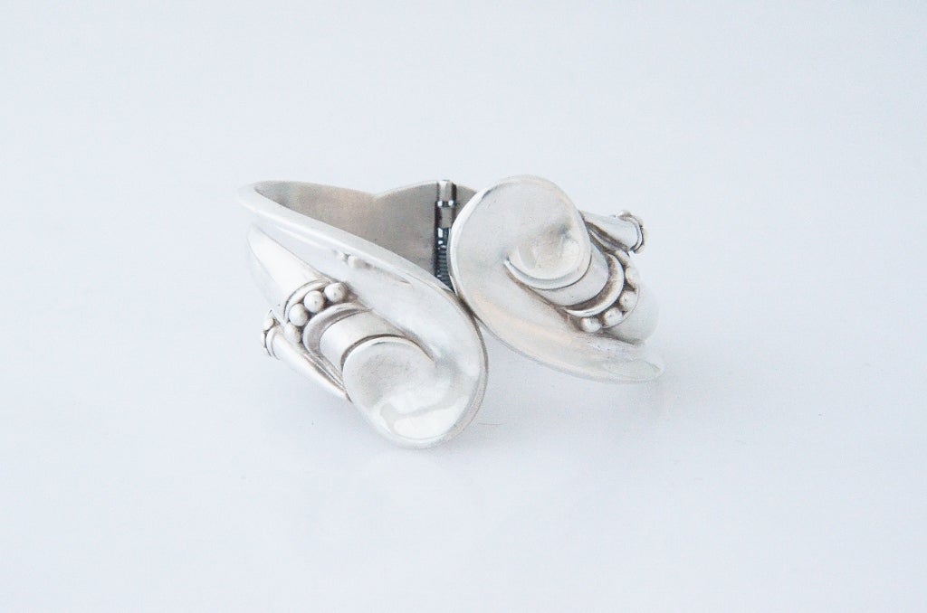 Being offered is a sterling silver hinged clamper bracelet by Margot De Taxco, of Mexico, in a modernistic, architectural motif with planes and many flat and curved surfaces.  It has a wearable length (inside circumference) of 7