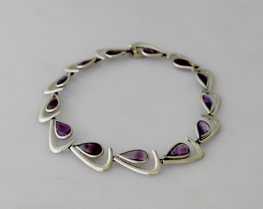 Being offered is a circa 1960s .970 silver and amethyst necklace by Antonio Pineda, of Taxco, Mexico, comprising boomerang motif links with amethyst tear drop stones. Dimensions 16 1/2 inches. Marked as illustrated. In excellent