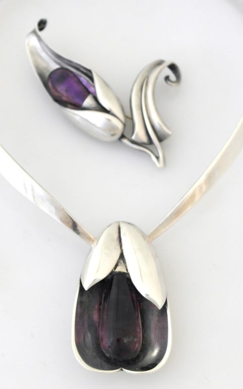 Being offered is a circa 1955 sterling silver necklace, bracelet, brooch and earrings from Los Castillo of Taxco, Mexico. in a modernist design, each piece with a large cabochon amethyst as if the center of a flower, the necklace on a tongue and