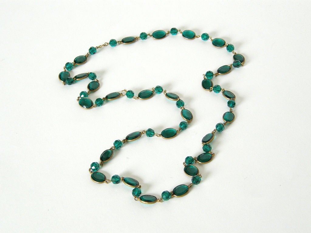 This sautoir has alternating faceted beads and faceted ovals in a rich, emerald green. The oval pieces are not pierced like the beads but rather set in brass frames.

Please contact us if you have any questions.