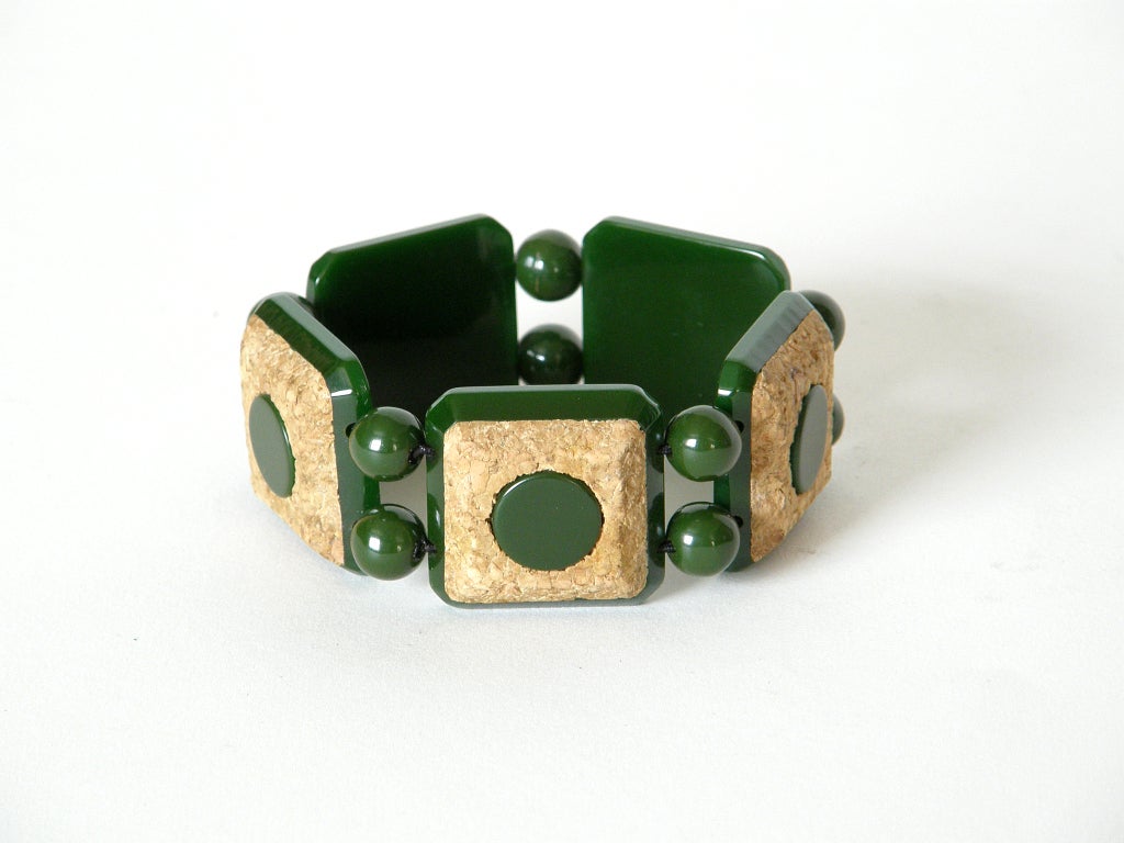 Forest green bakelite bracelet with boldly geometric circles and squares design. The square links are bakelite with inset pressed cork and a circle of bakelite at their centers. They are separated by round bakelite beads in a matching green. The