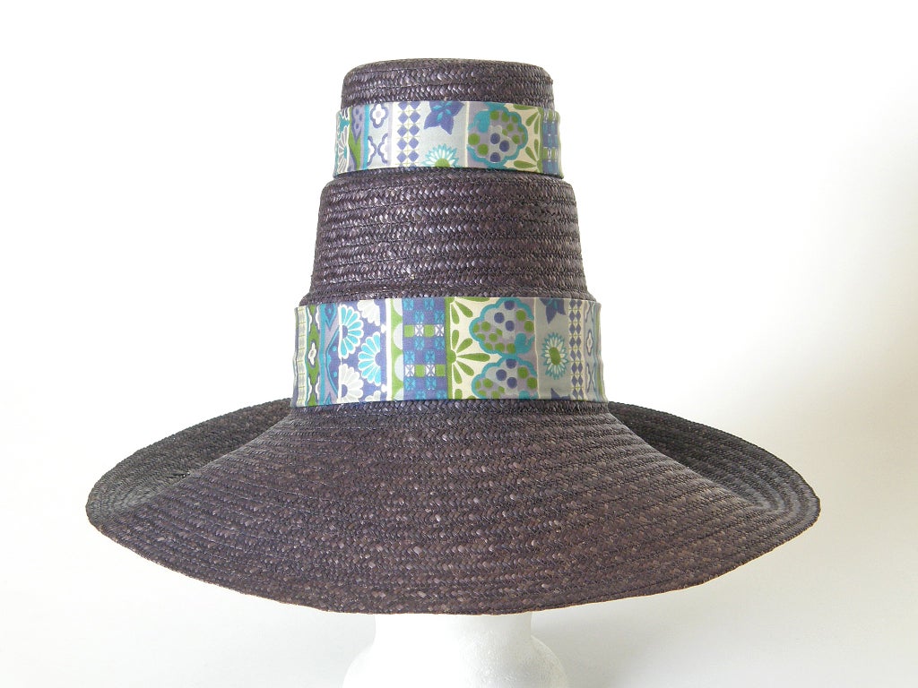 Wonderful straw hat with a broad brim and an extra tall, tiered  top. Wide bands of patterned ribbon run around two of the tiers. This fun beach or sun hat is a classic 1950s resort accessory, made in Italy for Marshall Field & Co. 

Measures