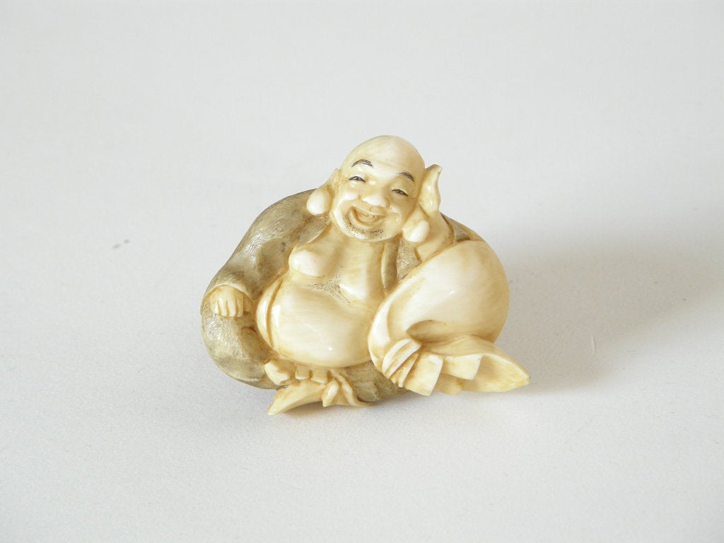 This happy Buddha brooch is deeply carved from a thick piece of ivory. The back of the ivory has the artist's or maker's mark, and the pin back is marked 