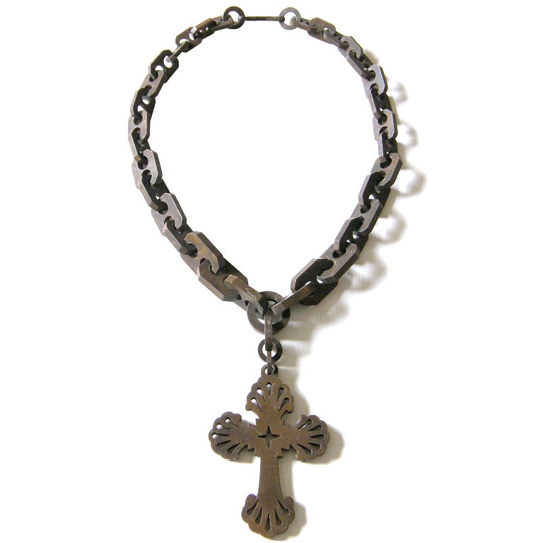 This beautifully carved, gutta percha necklace has a wonderful, Victorian Gothic quality. The chain is bold, and the graduated links each have two holes. The cross is pierced, and the ends of its limbs are fanned or scalloped. Cross measures 3 1/2