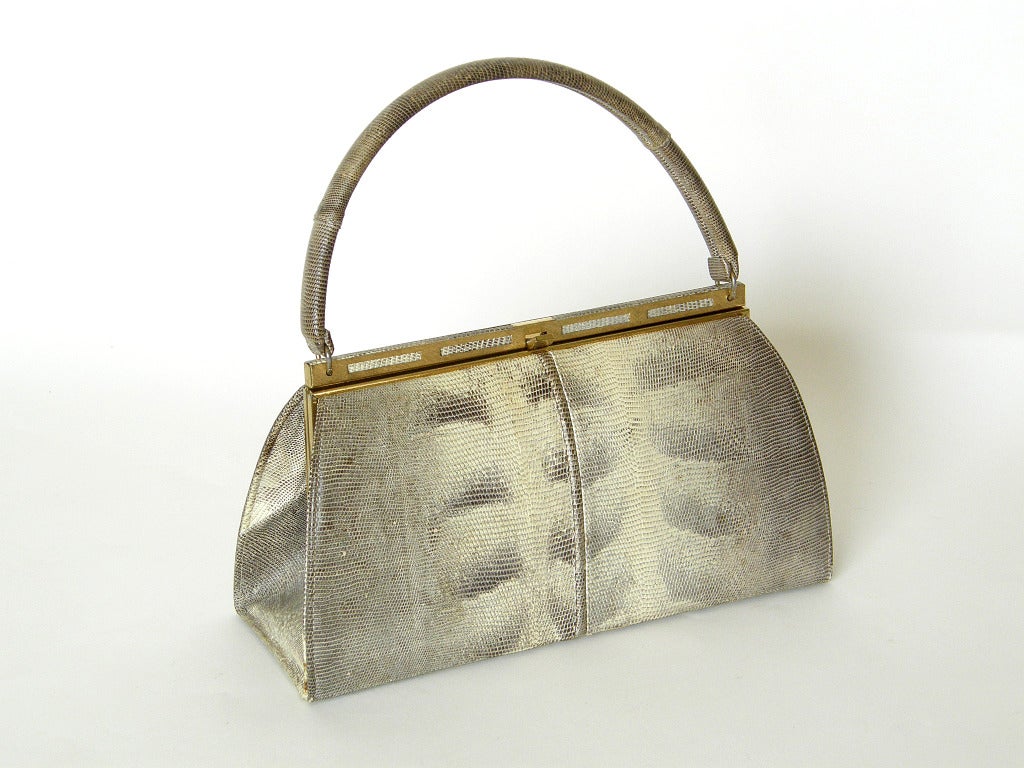 Lovely, lizard handbag with a rigid, arched top handle. This bag has a nice pattern to the skin in gray and cream. The leather lined interior is a peachy beige color.

Please contact us if you have any questions.