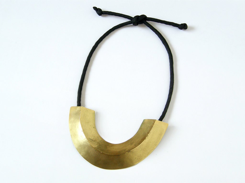 This handcrafted Mary McFadden necklace is bold, yet elegant. The large, gold-plated brass pendant has a simple, folded and bent form with a chic, warrior princess style that is a perfect balance of modern and primitive.

Please note that the width,