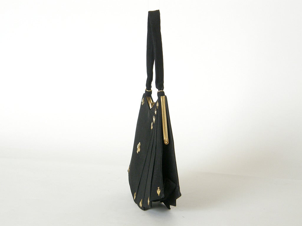 Gaming theme handbag by Anne-Marie in the shape of a hand of cards. The bag is covered in black suede with gold-plated brass hearts, diamonds, spades and clubs. The clasp is a realistic game die.

Anne-Marie had a shop within the famous Hotel