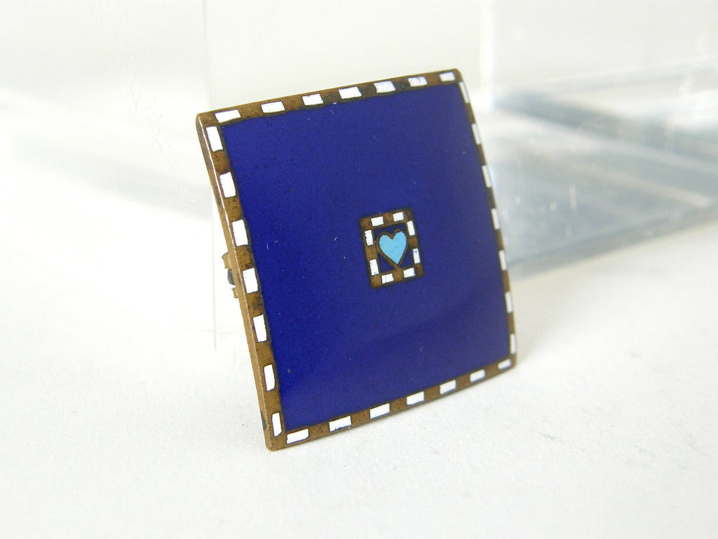Sweetly symbolic Wiener Werkstätte enameled brooch. The convex, brass square has a deep blue enameled field with a small baby blue heart in the center. The heart and the outer edges are trimmed with alternating rectangles of white enamel and plain
