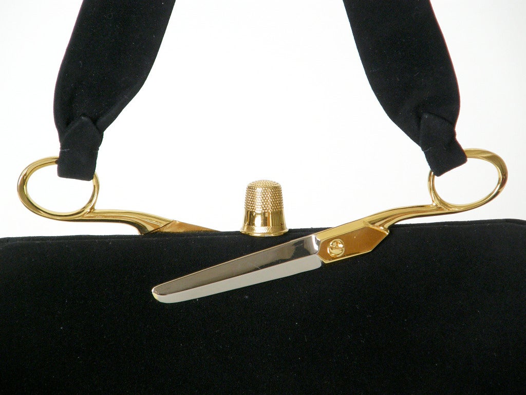 This exceptional Koret black suede handbag has dissected scissors attaching the handle to the frame and a thimble for the clasp. The gold plated thimble and gold and silver plated scissors halves are extremely realistic. The black leather lining has