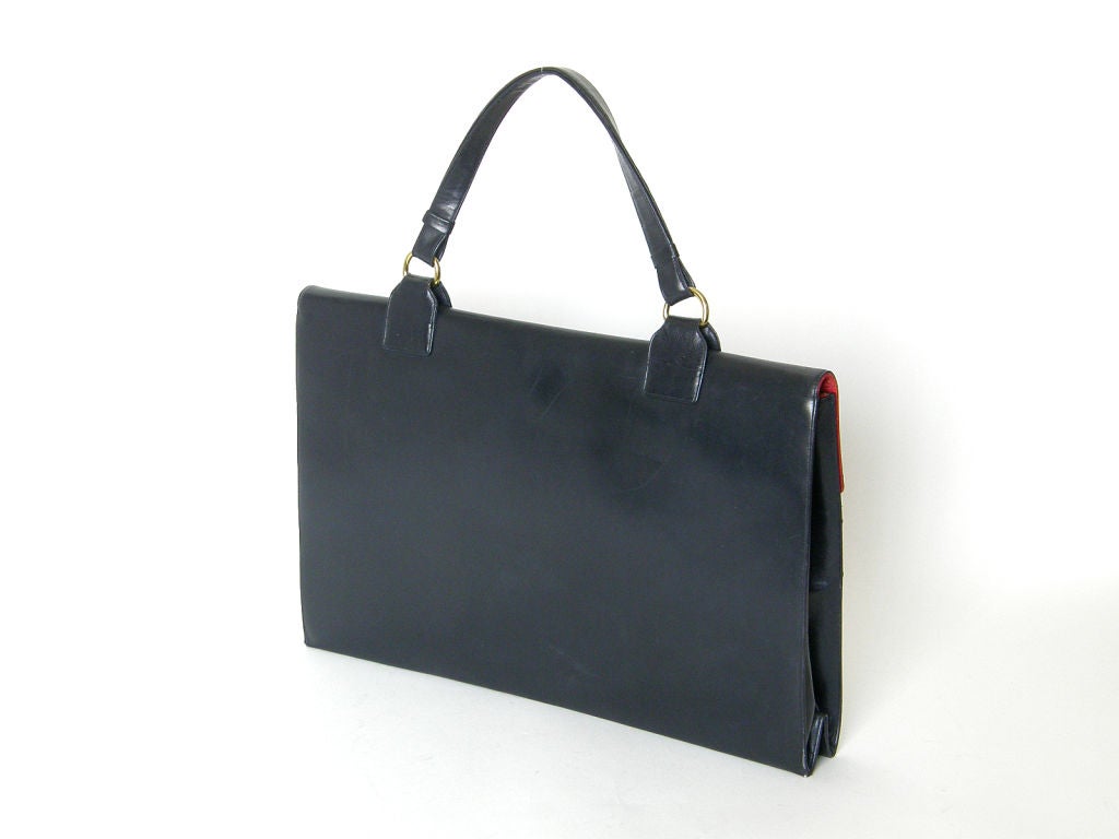 This Koret travel bag makes a very elegant briefcase. It has a dark navy leather exterior, and a lipstick red leather interior. The pocket on the outside has an attached file for important papers (passport, tickets, money). The file comes out of the
