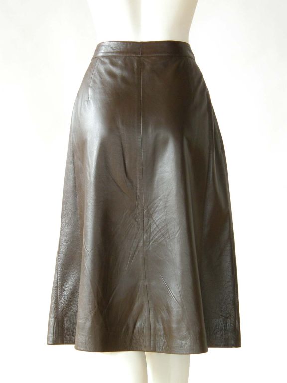 This classic, Gucci skirt is made from a buttery soft, brown leather. It has a simple A-line form with a long, deep double pleat down the front. It zips up the front and has 2 slant pockets with loop and button closures. It is fully lined with the