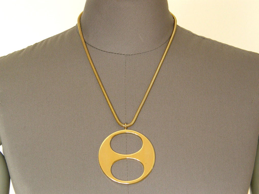 This modernist necklace was designed by Christian Dior and made in Germany in 1971. The round pendant is pierced with 2 elliptical shapes. It hangs from a rounded snake chain.

chain- about 20