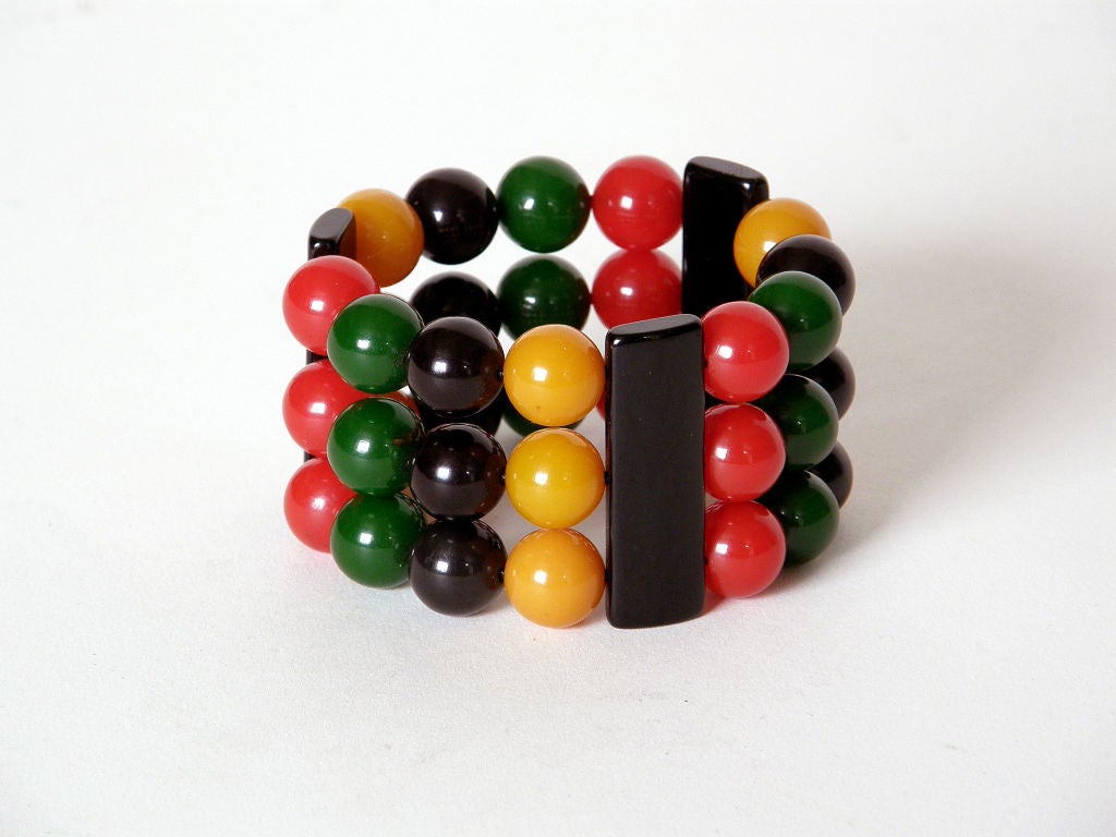 This colorful, multi-strand bakelite beads bracelet is like a beaded cuff with a close fit. The black bakelite bar shaped pieces keep the little yellow, black, green and red ball shaped beads in tidy rows. It's strung on elastic cord and slips on