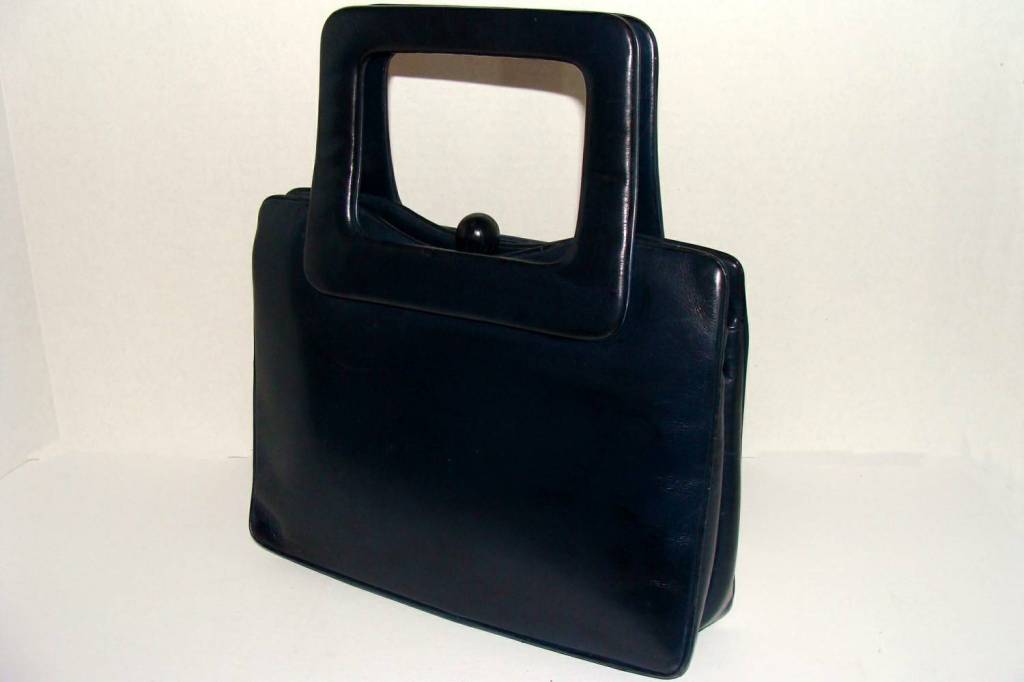 Sophisticated and timeless navy calfskin handbag with a rectilinear format--a square base with square handles--and a surprising ball clasp.

The bag has two large exterior pockets which flank the secure center section.  Inside, there are a few