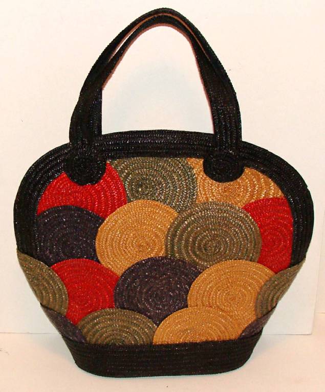 Oversize woven handbag with double handles.  Black handles, edges and base, with red, green, yellow and navy circles on front and back.  It is in great condition.  Its design makes it a show-stopper and its size adds to its practicality.  