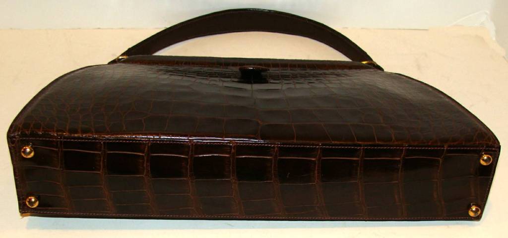 Rich brown center skin alligator on front and back.  
Classic, sleek design.  Tight and fine stitching.  Supple skins with no cracking or lifting scales.  Beautiful modernist hardware was used on the clasp and the top corners.

We specialize in