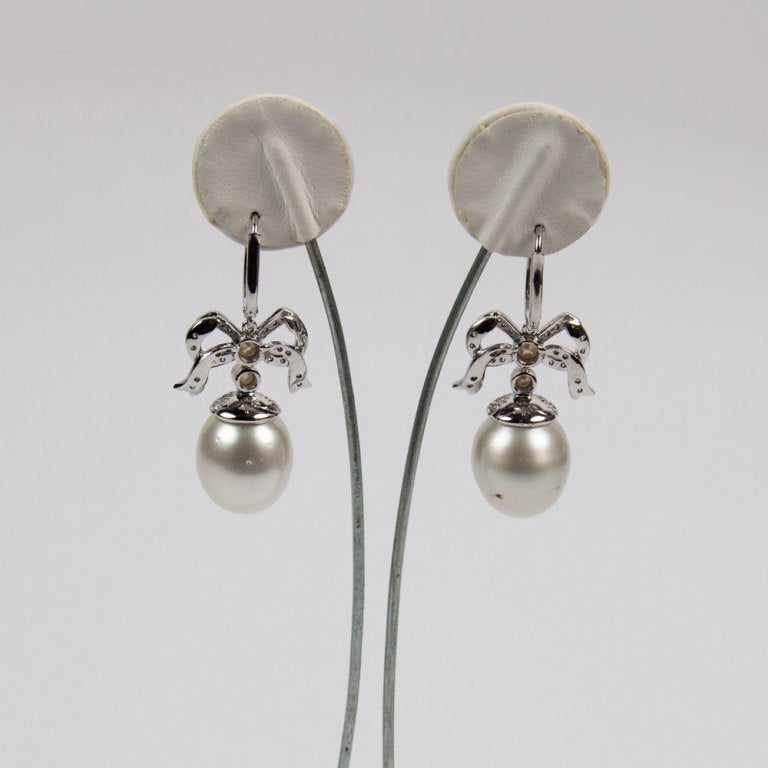 Beautiful pair of South Sea Pearl and Diamond Bow Earrings mounted in white 18k Gold 
Each earring centers a Beautiful South Sea Pearl in Diamond encrusted cap, suspended from a bow and two small pearls, each measuring approx. 3.2mm x 3.68mm. Each