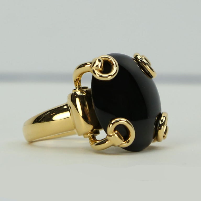 Fabulous signed Gucci 18K Yellow Gold Onyx Ring, featuring a round cabochon black onyx stone set in a stylized stirrup prong mounting.  
Top of ring measures 24mm across by 15mm thick; approx. weight 35 ct. approx weight of ring: 25.4 gm. Ring