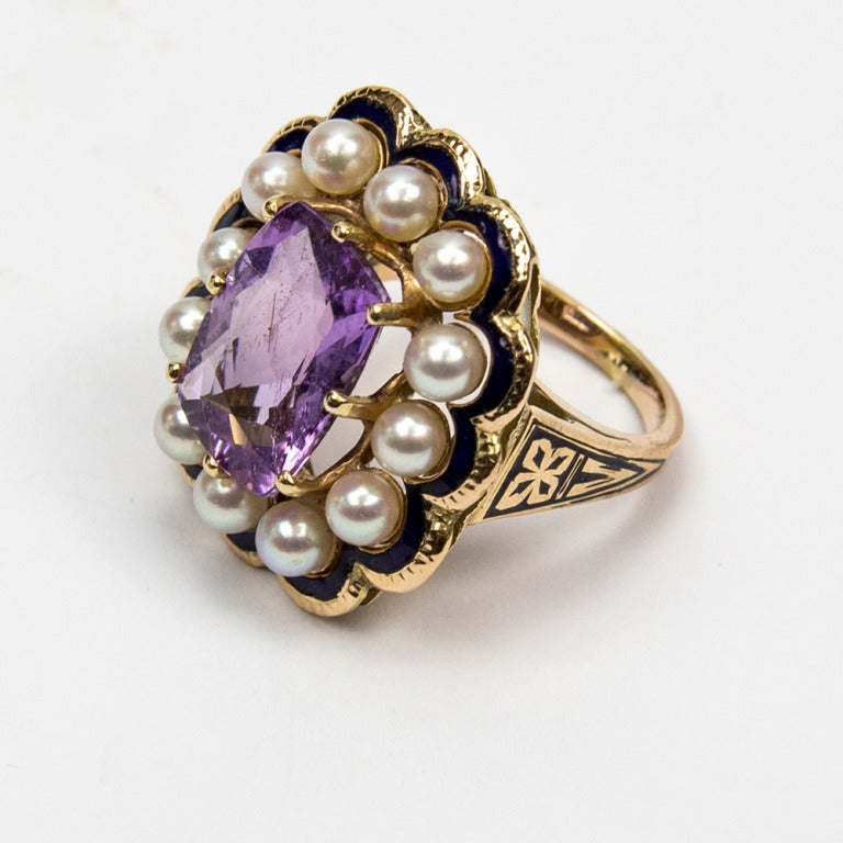 An Outstanding Early 1900s Edwardian Ring, center set with a faceted cushion-cut purplish blue Indicolite Tourmaline surrounded by twelve Pearls Gold enhanced with blue enamel accents; in 14k yellow gold; 11.6gm. Ring size: 6+ Step out in Style and