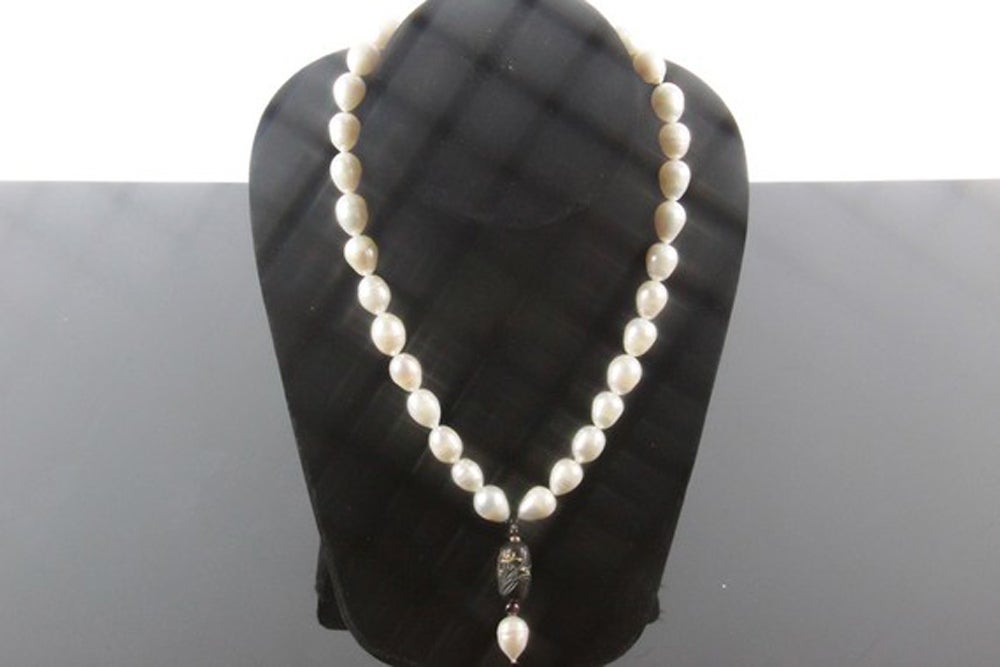 Stunning Baroque Fresh Water Pearls suspending a Rare Antique Signed Bronze *Ojime Bead beautifully worked with Orchid Flowers. Approx. length: 17” drop size: 1 ¾”. Sterling Silver Barrel style clasp closure. **Only Ojime bead is 19th