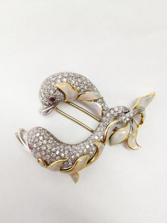 Stunning Double Dolphin Brooch, encrusted with vivid round dazzling brilliant cut diamonds; enhanced with creamy beige enamel and ruby eyes. This elegant piece has approximately 3.85 carat. of diamonds, mounted in 18 Karat white and yellow gold.
