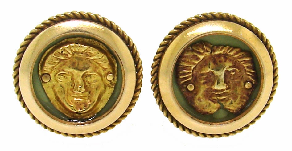 A pair of clip-on earrings created by Cartier in circa 1950's. Their design is inspired by ancient Roman motif. The earrings are made in the shape of a button with gold men's faces inlaid in light green enamel and framed in gold circle. The men have