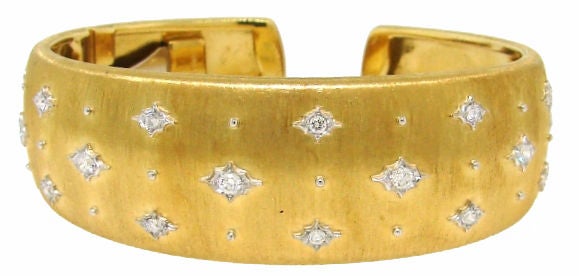 Signature Buccellati bangle created in Italy. The highlights of this bracelet are - typical Buccellati satin finish on yellow gold and twenty three round diamonds bezel set in tastefully engraved white gold accents.<br />
The bangle is slightly