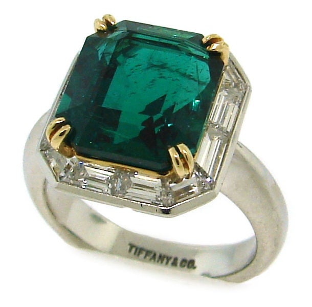 Classic cocktail ring created by Tiffany & Co. in the 1960's. Can also be a non-traditional engagement ring. 
The highlight of the ring is 6.26 carats cut-cornered rectangular step cut emerald. It is surrounded with baguette cut diamonds and set in