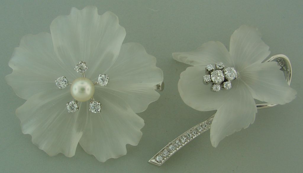 Dazzling and delicate duo of flower pins created in Switzerland in the 1930's. The carving and design are just stunning! Beautiful old cushion cut and Old European cut diamonds. An Akoya pearl in the center of the bigger flower. 
The piece is