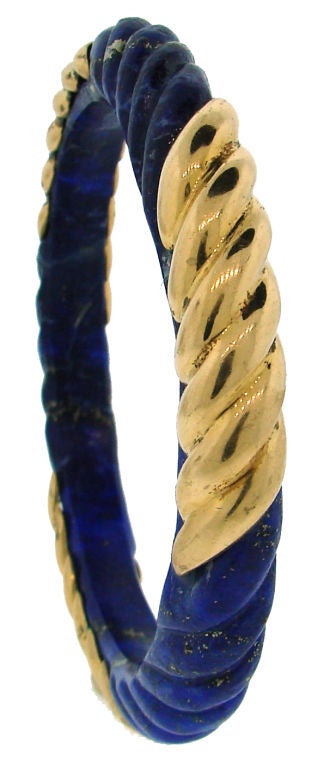 Colorful bangle created by Van Cleef & Arpels, New York in the 1970's. Beautiful carved lapis lazuli with three gold overlaid parts repeating the carving pattern.
The bangle fits up to 7.5