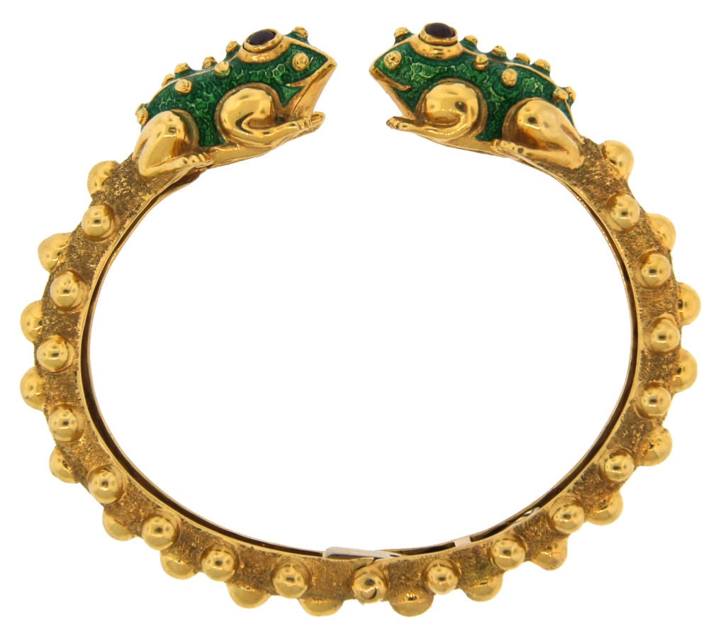 Cute, joyful and recognizable frog bangle created by David Webb in the 1980's. Made of yellow gold, inlaid with green enamel and accentuated with ruby cabochons.<br />
Fits up to 6.5
