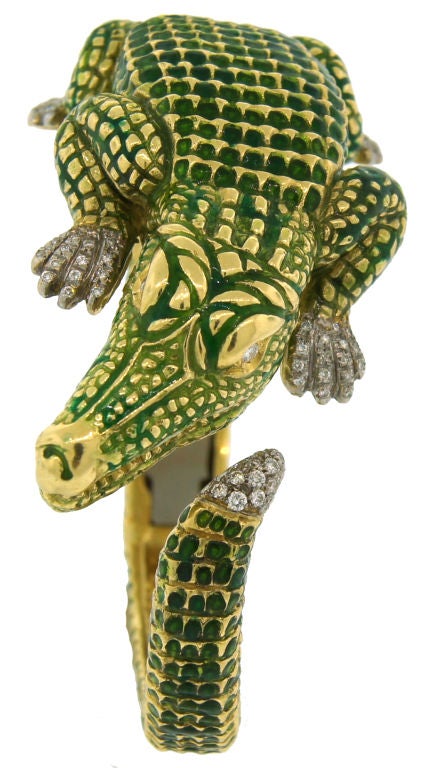 Fun and cute bangle created in the shape of an alligator by Seaman Schepps in the 1990's. It is made of yellow gold and green enamel; the alligator's eyes, feet and tail tip are accentuated with round diamonds.<br />
Fits up to 7