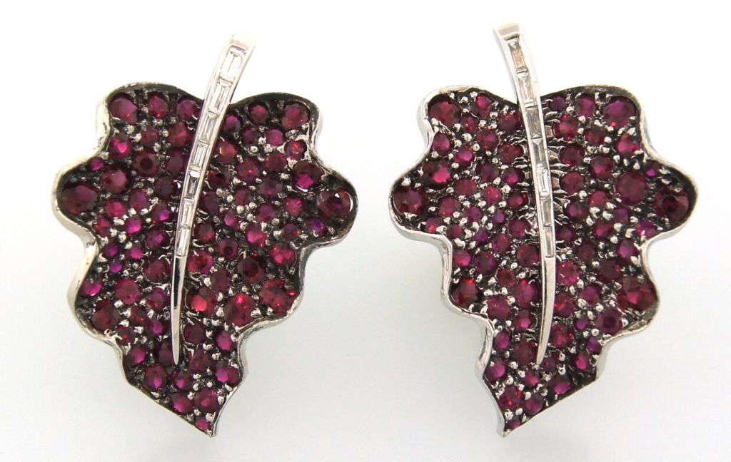 Lovely elegant earrings inspired by floral motif and created by Fred Leighton in the 1990's. They are made of white gold in the shape of a leaf and encrusted with rubies and diamonds. Three-dimensional texture of the leaf is accentuated by using a 