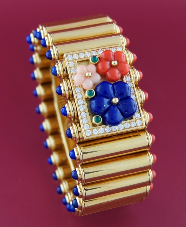 Stunning bracelet created by Van Cleef & Arpels in the 1960's. The highlight of this unique piece is a removable central plaque encrusted with coral, lapis lazuli, round brilliant cut diamonds and cabochon emeralds. The plaque can be replaced with a