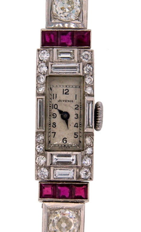Unique and gorgeous Art Deco jeweled ladies watch created by Juvenia around 1920's. The watch has a Swiss movement, is manual wind. It features a narrow rectangular face encrusted with diamonds and rubies. The dial is 7 x 14 mm, the face is 11 x 24