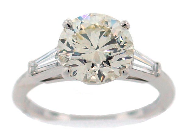 Classy and timeless engagement ring created by Tiffany & Co. featuring a beautiful 2.61-ct round brilliant cut diamond set in platinum and accentuated with two tapered baguette diamonds to the sides. The ring is size 6-1/4 and can be sized if