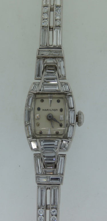 Classy and timeless diamond lady's watch created by renowned American firm Hamilton in the 1960s. This lovely, feminine watch is made of platinum and encrusted with round brilliant and baguette-cut diamonds. It fits up to 7
