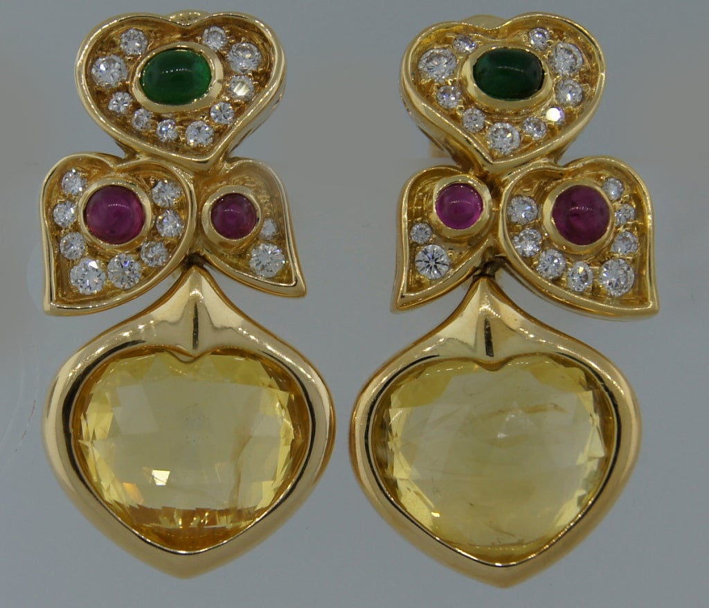 Stunning heart motif earrings created by Bulgari in Italy in the 1980's. Feature two heart-shape yellow sapphires accented with diamonds, rubies and emeralds. The earrings are clip-on; however posts can be added if needed.