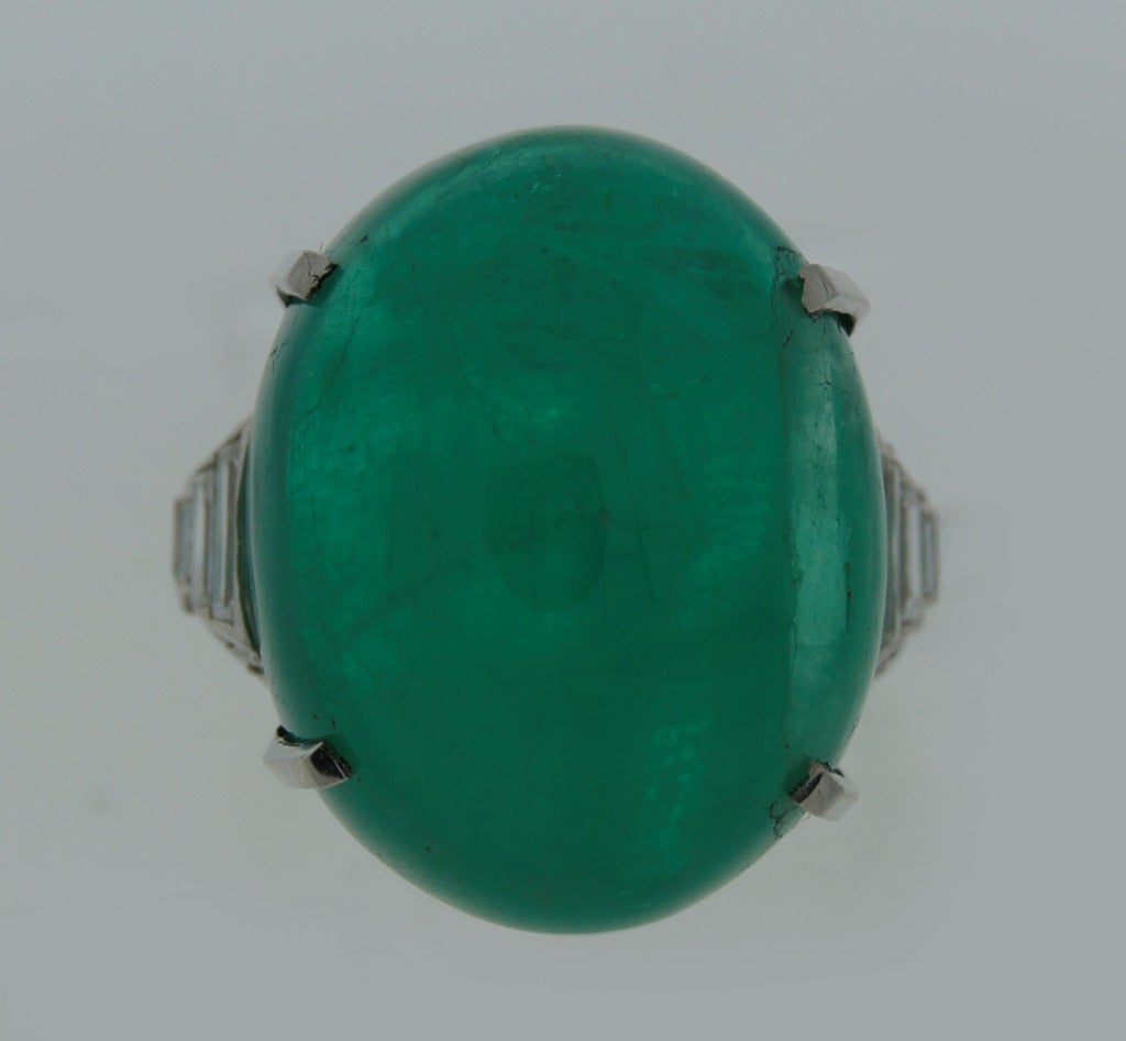 Gorgeous cocktail ring created in the 1960's. Features a  30-ct oval cabochon emerald accented with diamonds and set in platinum. 
The ring is size 8.25 and can be sized if needed.
The emerald is natural and has few inclusions one of which almost