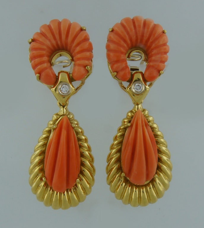 Colorful, bold yet feminine earrings created by Van Cleef & Arpels in Italy in the 1970s. 
Feature beautiful carved coral set in 18k yellow gold and accented with round diamond connecting the coral parts. 
The earrings are 2